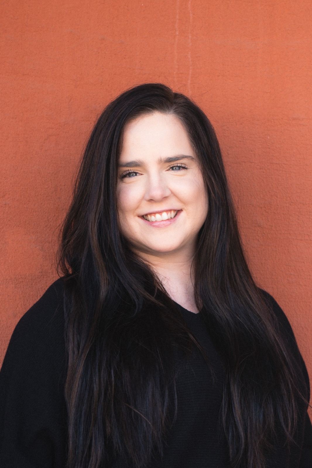 Cecilia Wooten smiling warmly against a terracotta wall